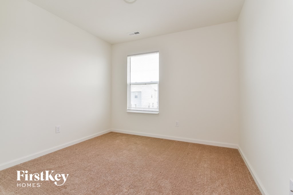 A room with a carpeted floor and a window.
