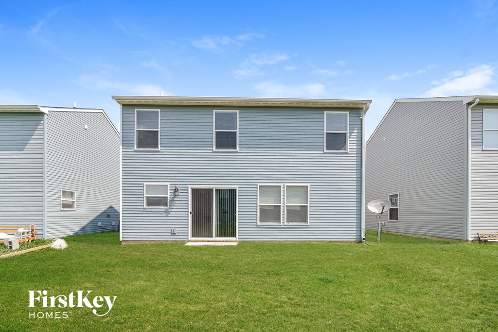 A FirstKey Homes sign is on a grassy area in front of a grey house.