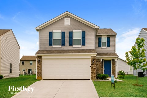 a tan house with blue shutters and a blue driveway