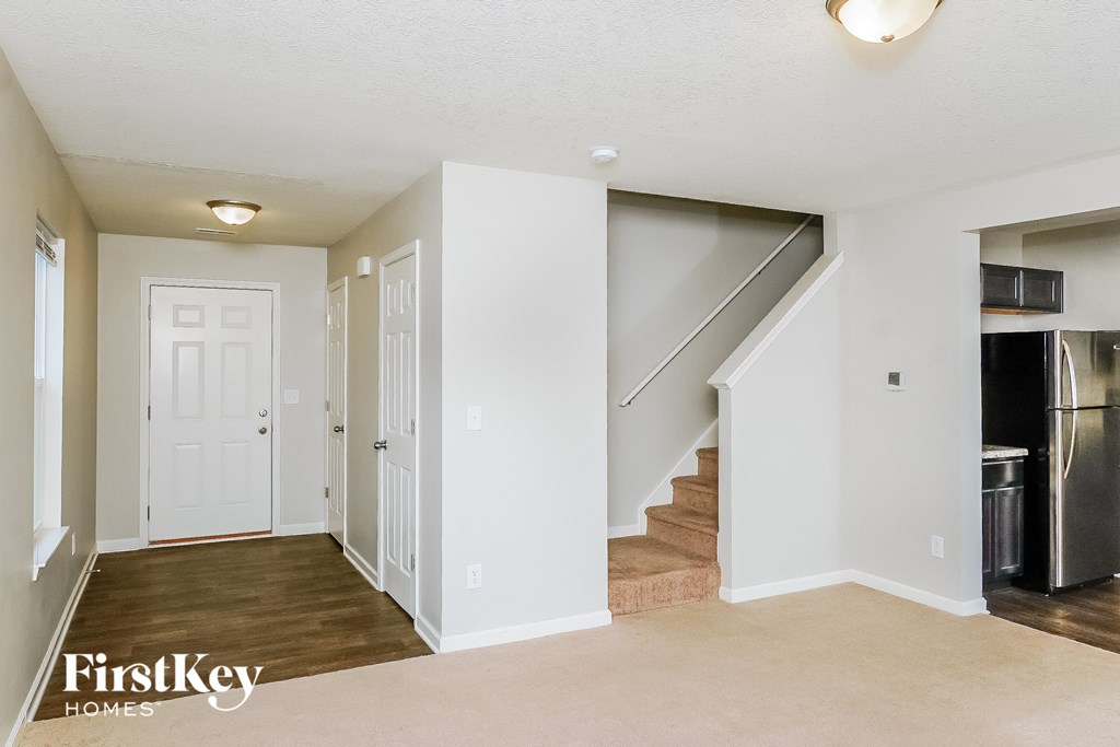 a renovated living room with a staircase and a kitchen