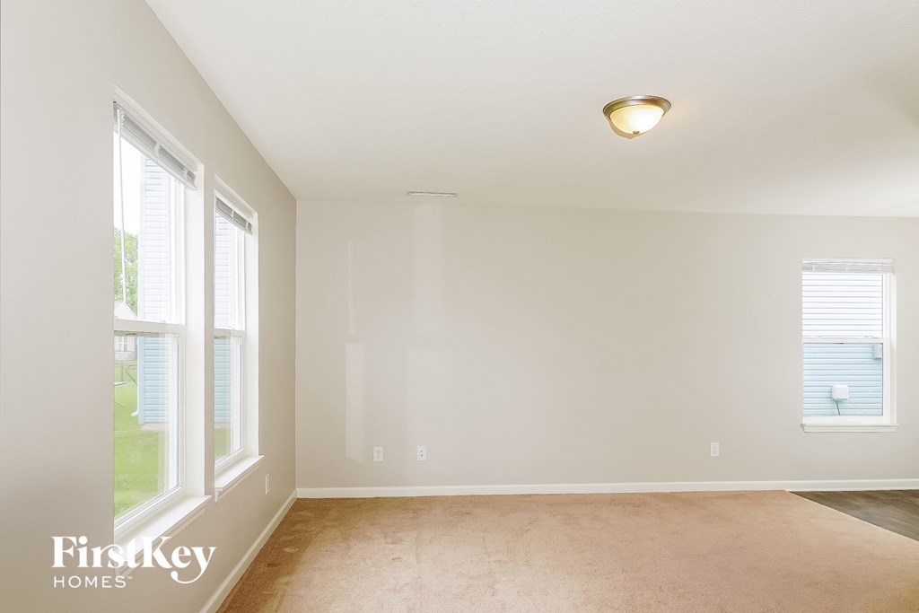 a living room with a carpet and two windows