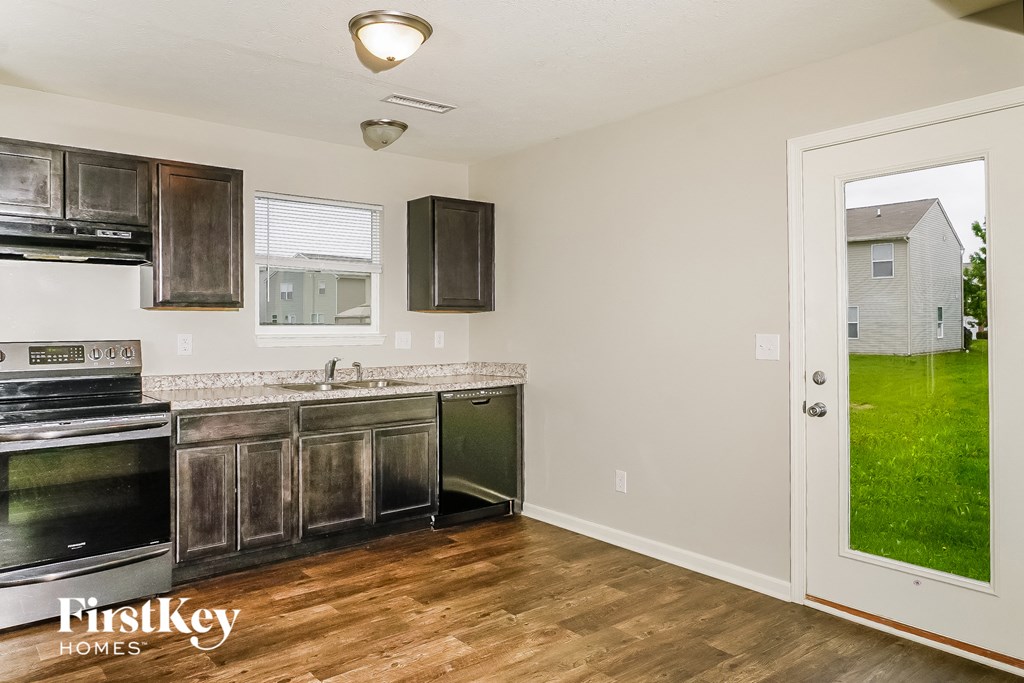 a kitchen with wood flooring and a door to a yard