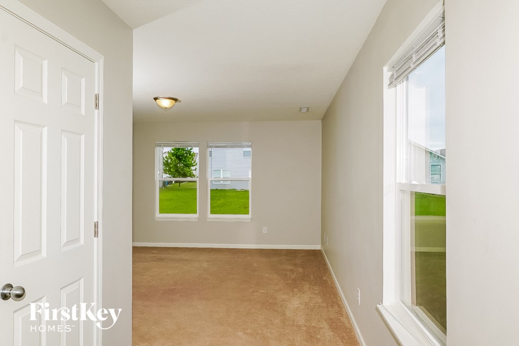 a room with a carpeted floor and two windows