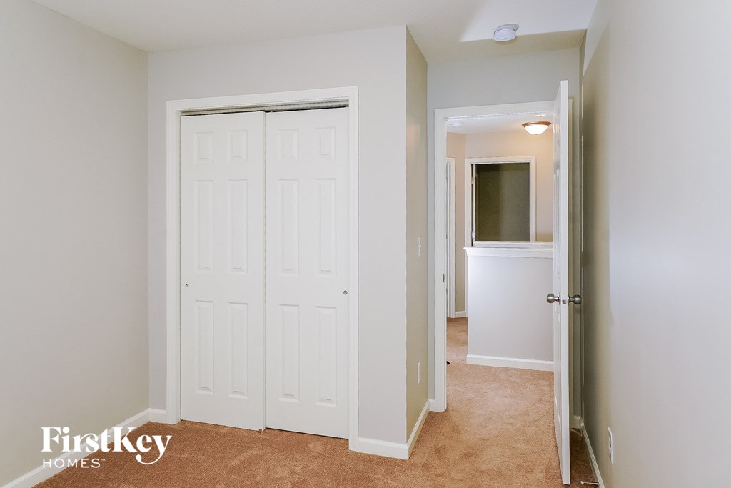 a bedroom with a closet and a white door and a hallway with a door open