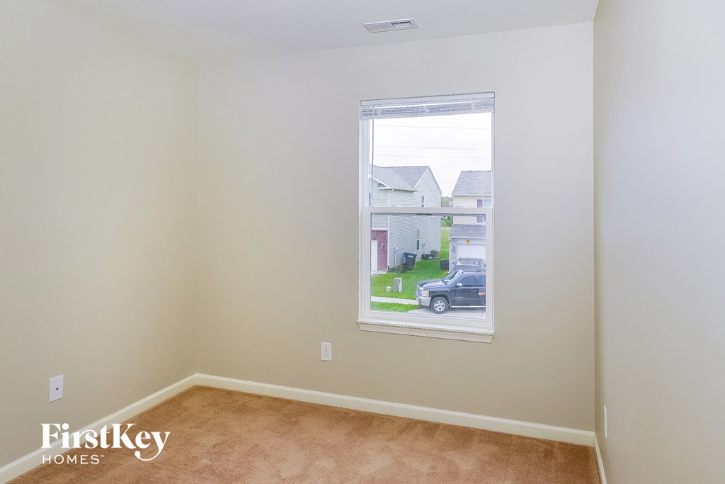 a bedroom with a large window and a carpeted floor