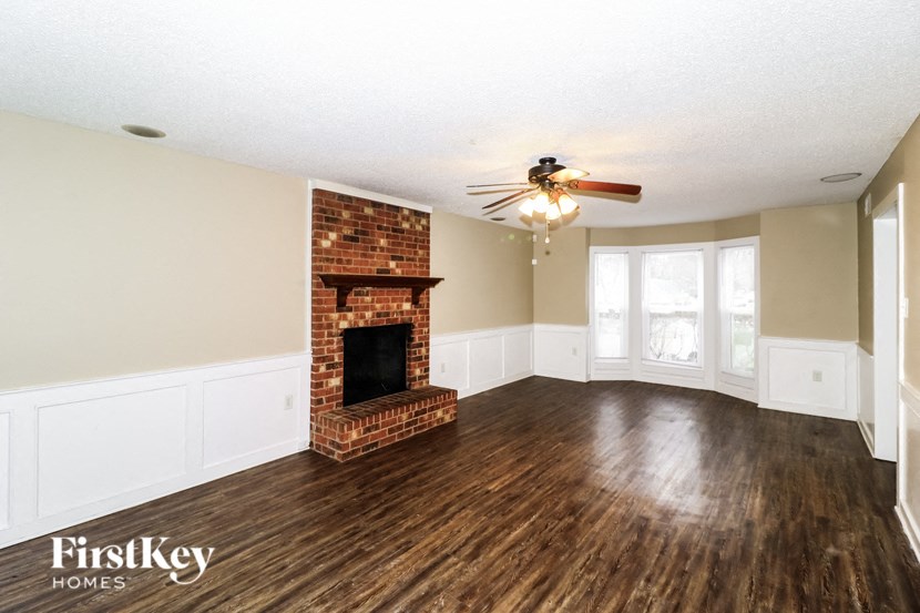 A room with a brick fireplace and wooden floors.