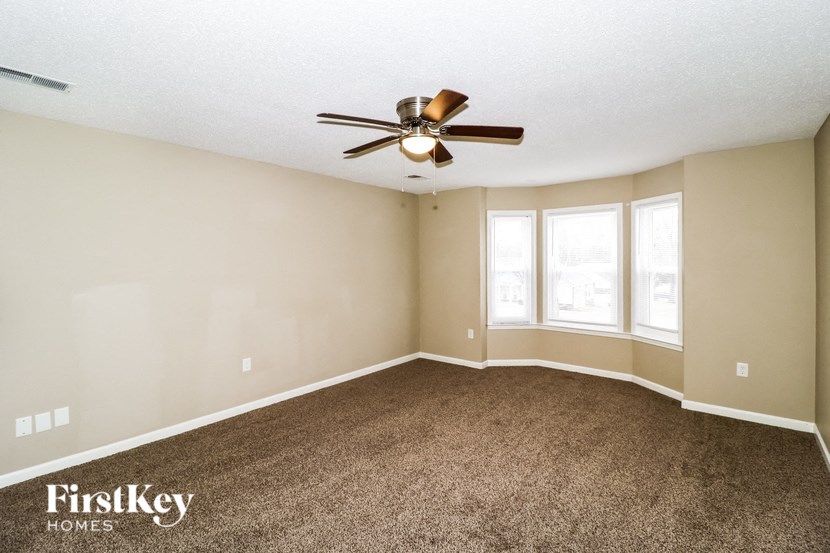 A spacious room with a ceiling fan and carpeted floor.