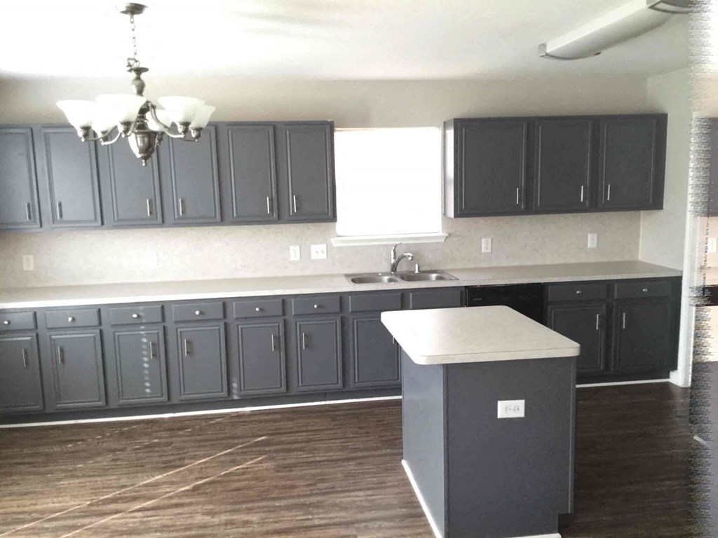 A kitchen with dark grey cabinets and a white island.