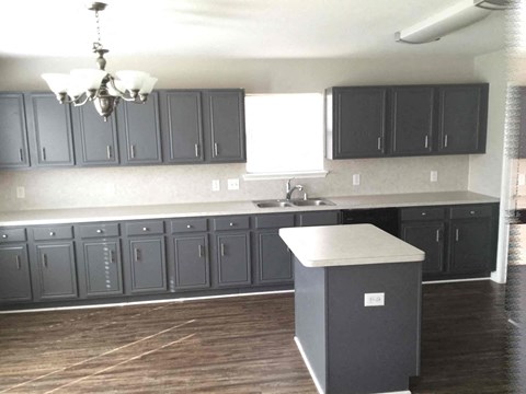 A kitchen with dark grey cabinets and a white island.