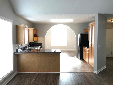 A kitchen with wooden cabinets and a black refrigerator.