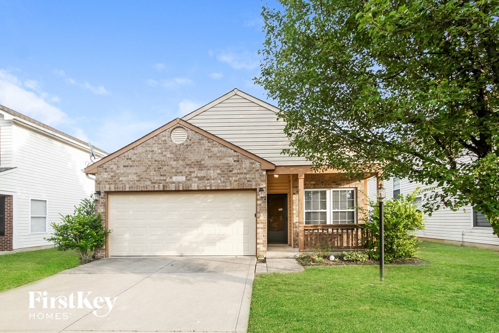 a brick house with a white garage door in front of a green lawn