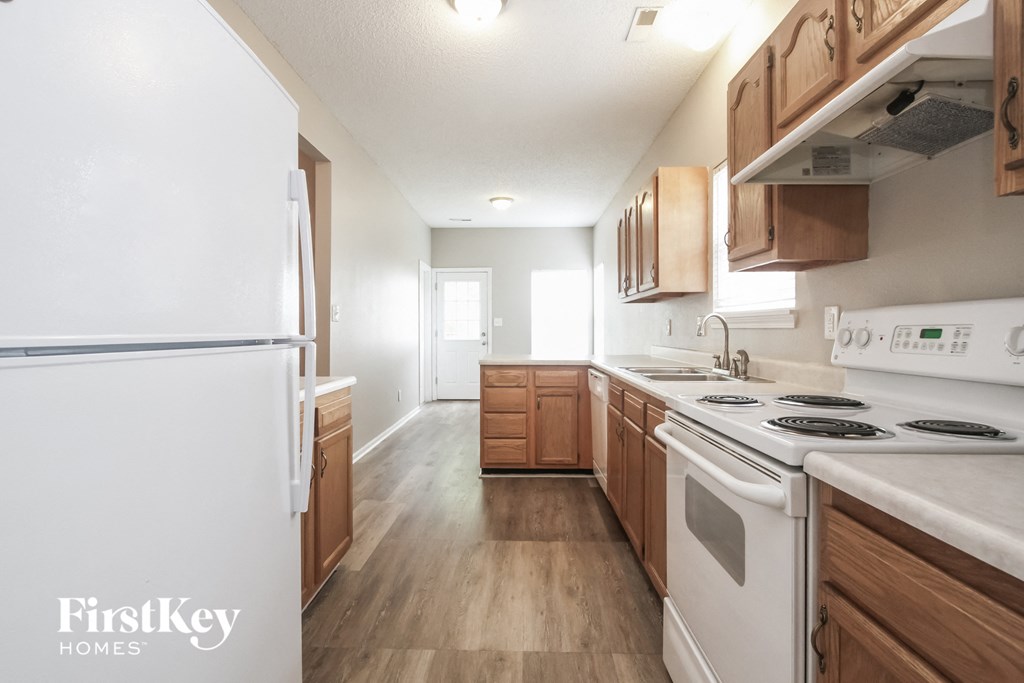 an empty kitchen with white appliances and wooden cabinets
