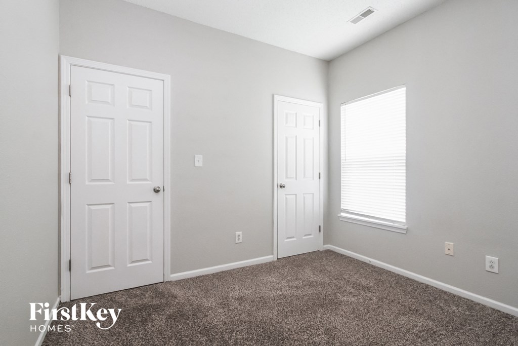 a bedroom with two doors and a carpeted floor and a window