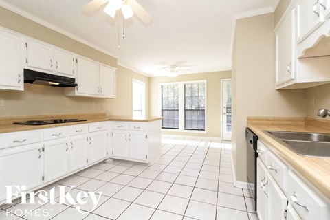 A kitchen with white cabinets and a tile floor.