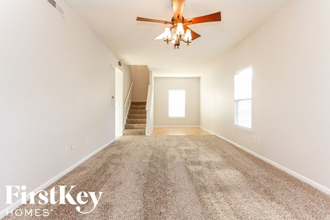A spacious room with a carpeted floor and a ceiling fan.