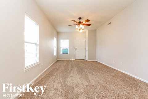 A spacious room with a carpeted floor and a ceiling fan.