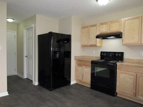 A black refrigerator and oven in a kitchen with wooden cabinets.