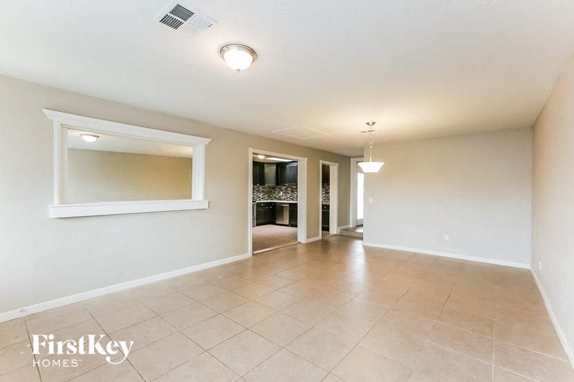 A spacious room with a tiled floor and a large mirror on the wall.