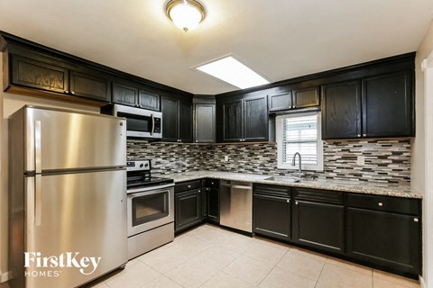 A kitchen with black cabinets and a stainless steel refrigerator.