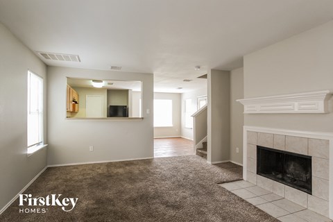 A spacious living room with a fireplace and a carpeted floor.
