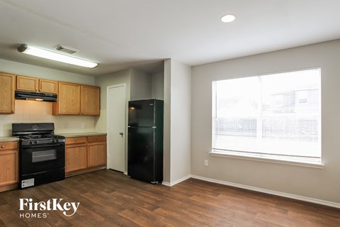 A kitchen with wooden cabinets and a black fridge.
