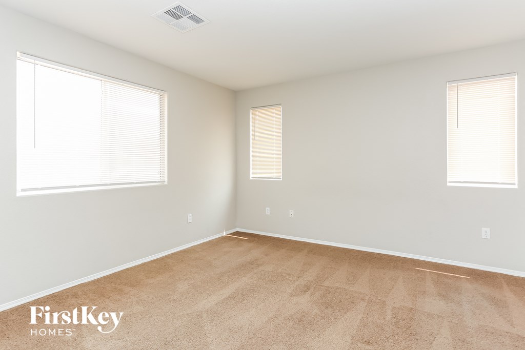 a bedroom with a wooden floor and two windows