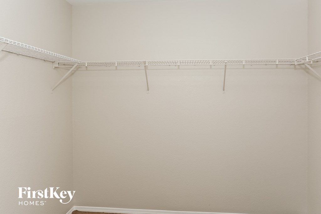 a walk in closet with white walls and a white hanger rack on the wall