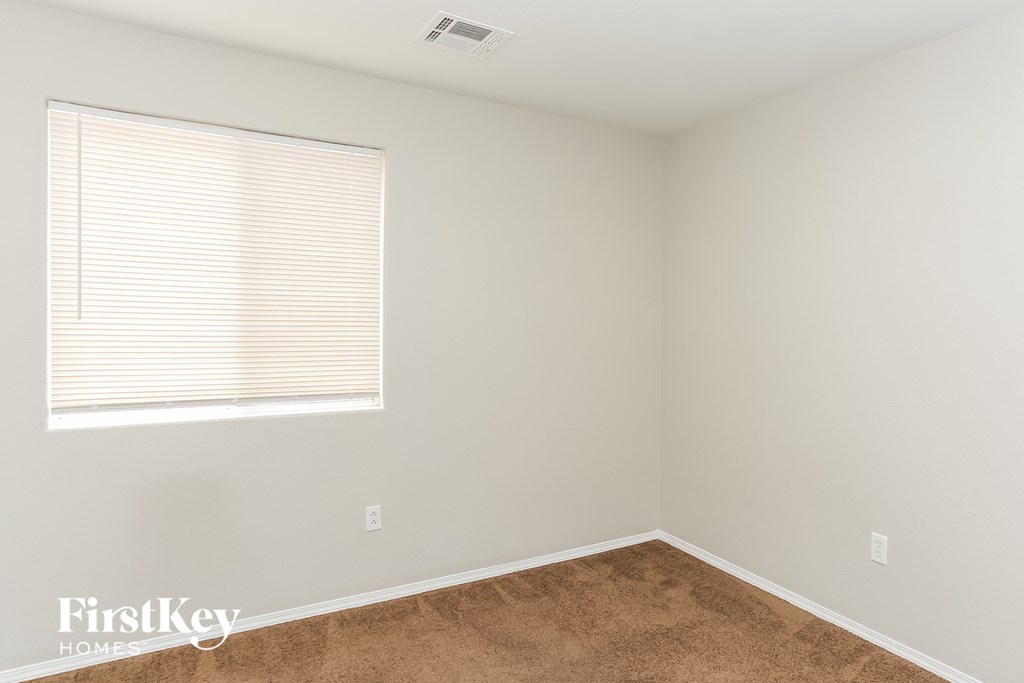 a bedroom with white walls and a window and a brown rug
