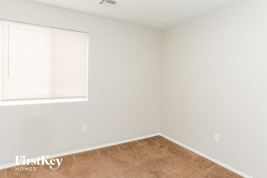 a bedroom with white walls and a window and a carpet