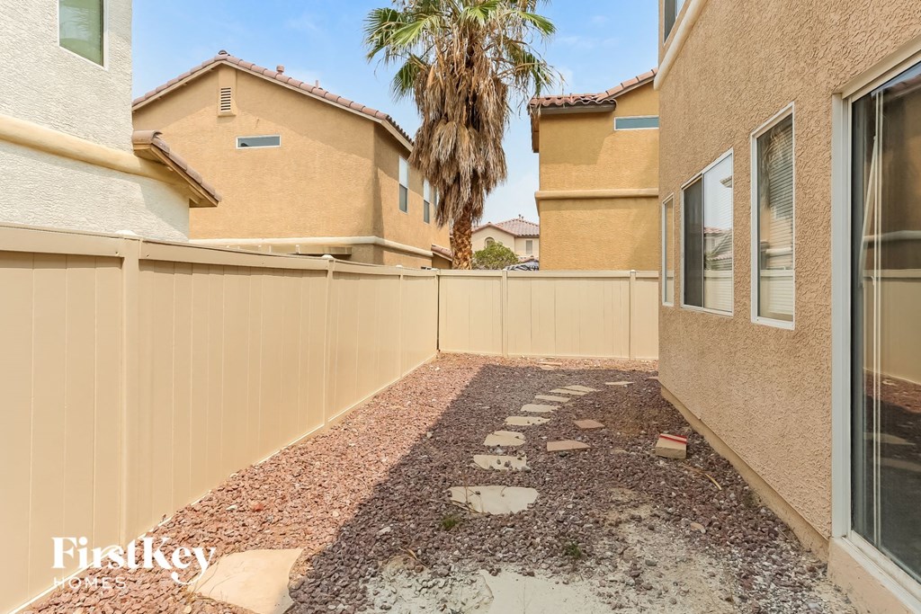 a backyard with a fence and a house with a palm tree