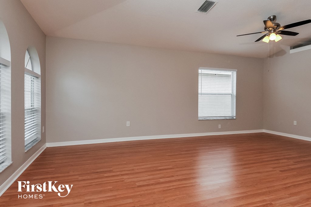 an empty living room with wood floors and a ceiling fan