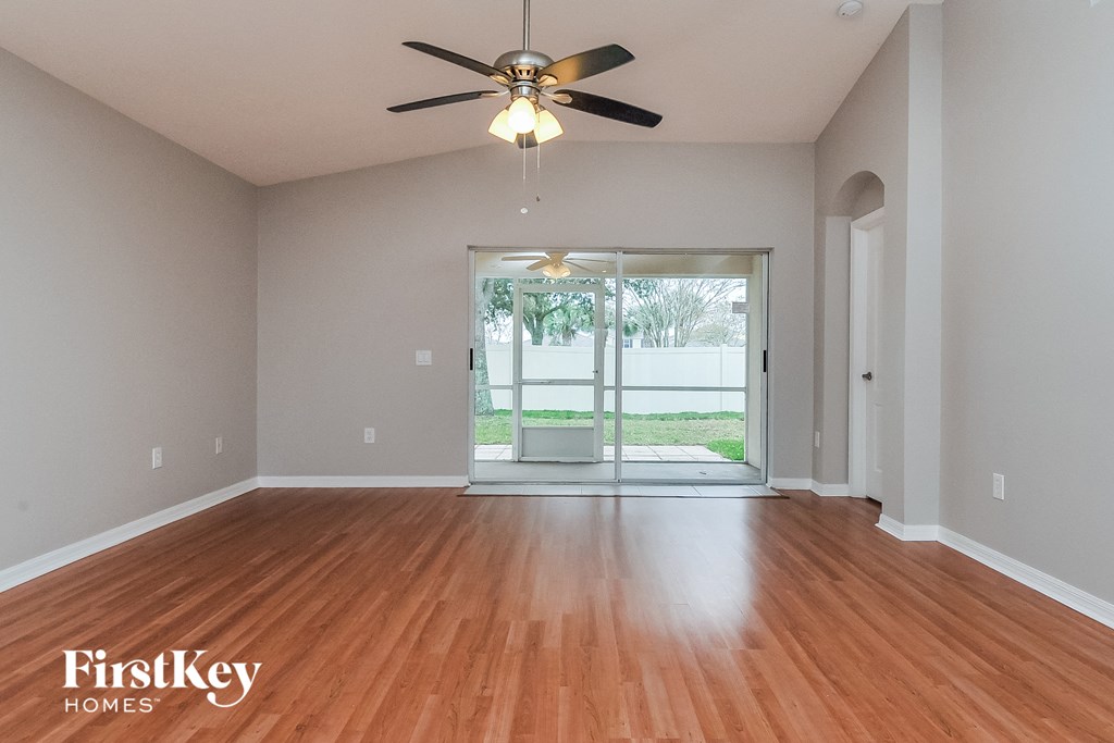 an empty living room with wood floors and a ceiling fan