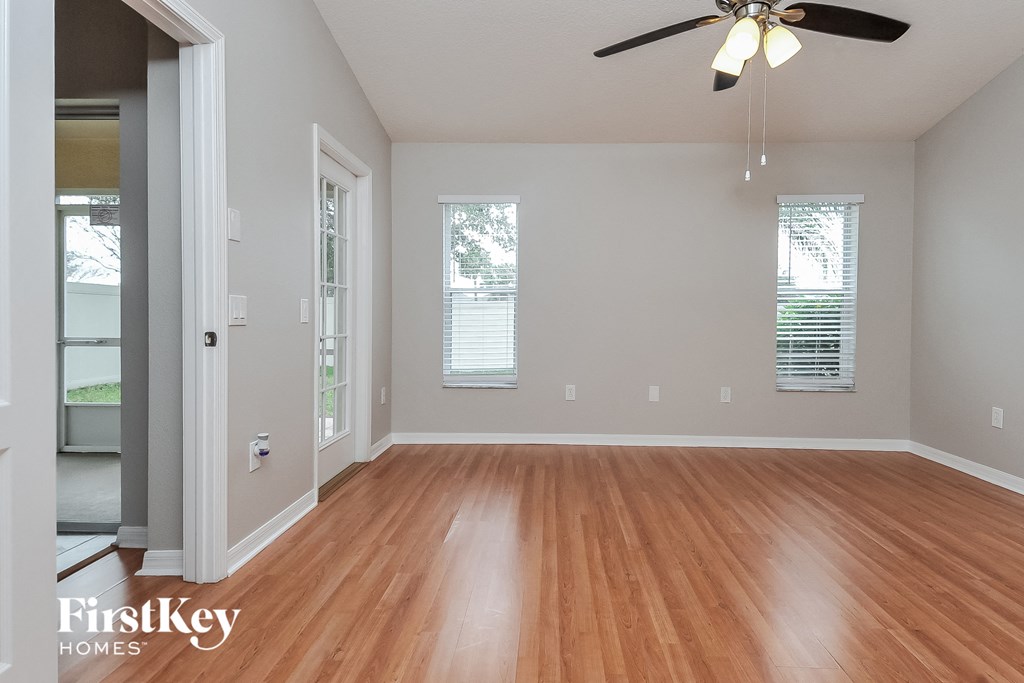an empty living room with wood floors and a ceiling fan