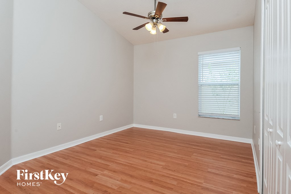 a bedroom with hardwood flooring and a ceiling fan