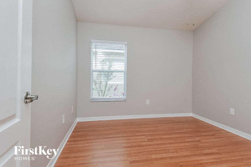 an empty room with wood floors and a window