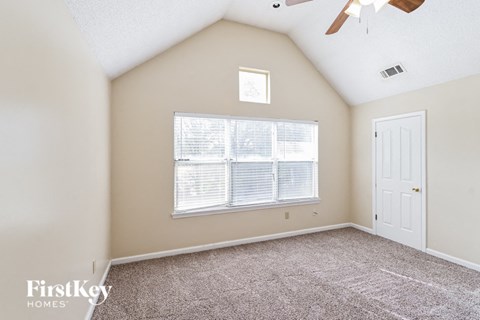 the master bedroom has a large window and carpeted flooring