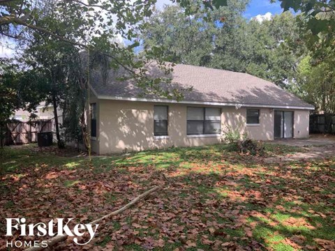 a small house with a yard with fallen leaves on the ground