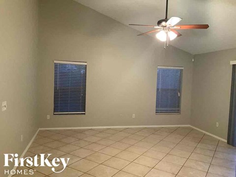 an empty living room with a ceiling fan and a tiled floor