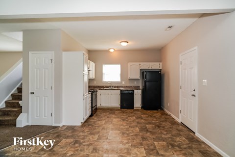 A kitchen area with a black fridge and a stove top oven.