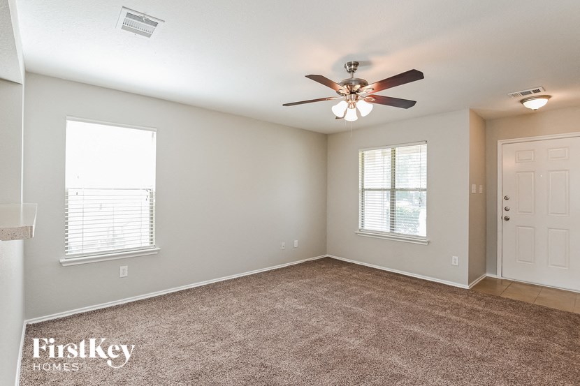 an empty living room with a ceiling fan