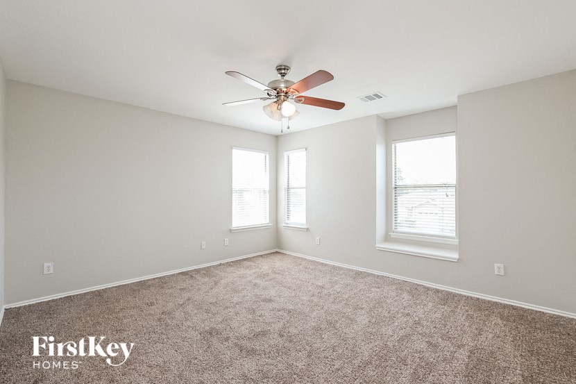 a bedroom with a ceiling fan and two windows
