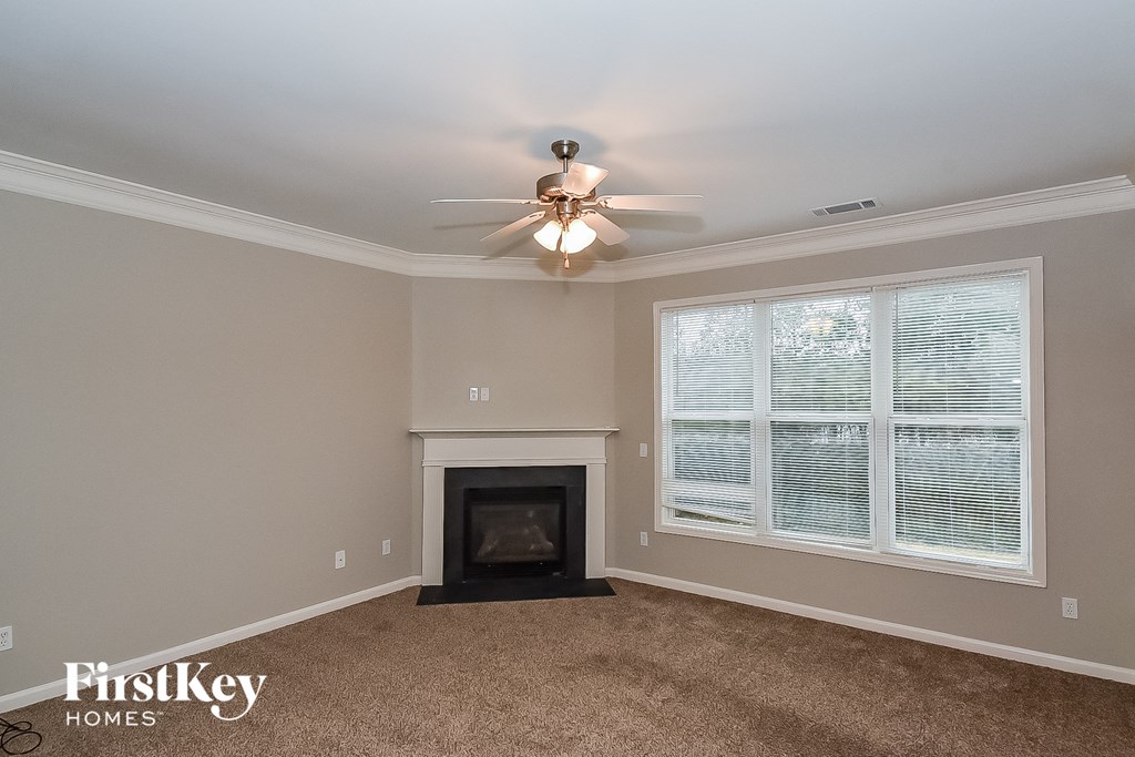 A living room with a fireplace and a ceiling fan.
