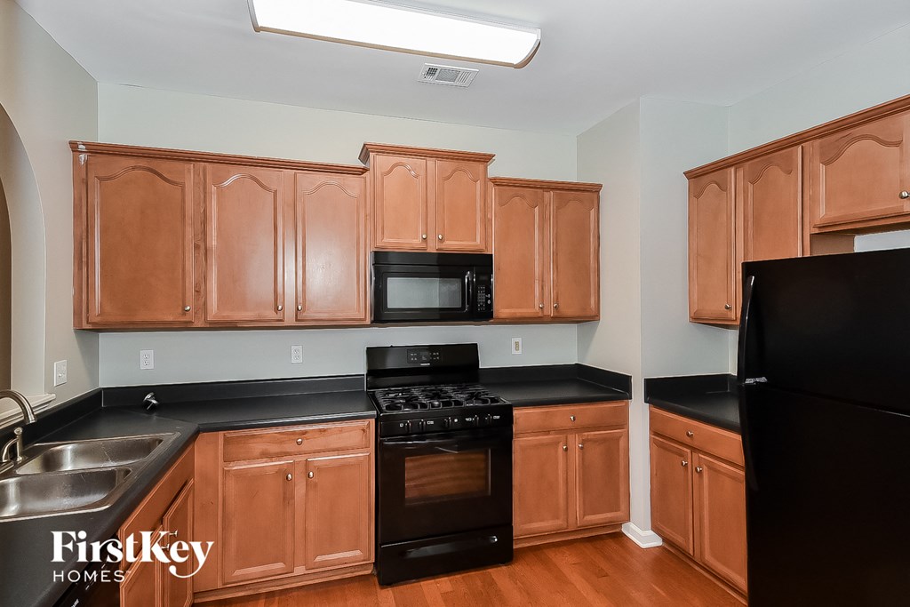 A kitchen with wooden cabinets and black appliances.