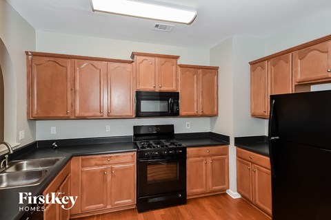 A kitchen with wooden cabinets and black appliances.