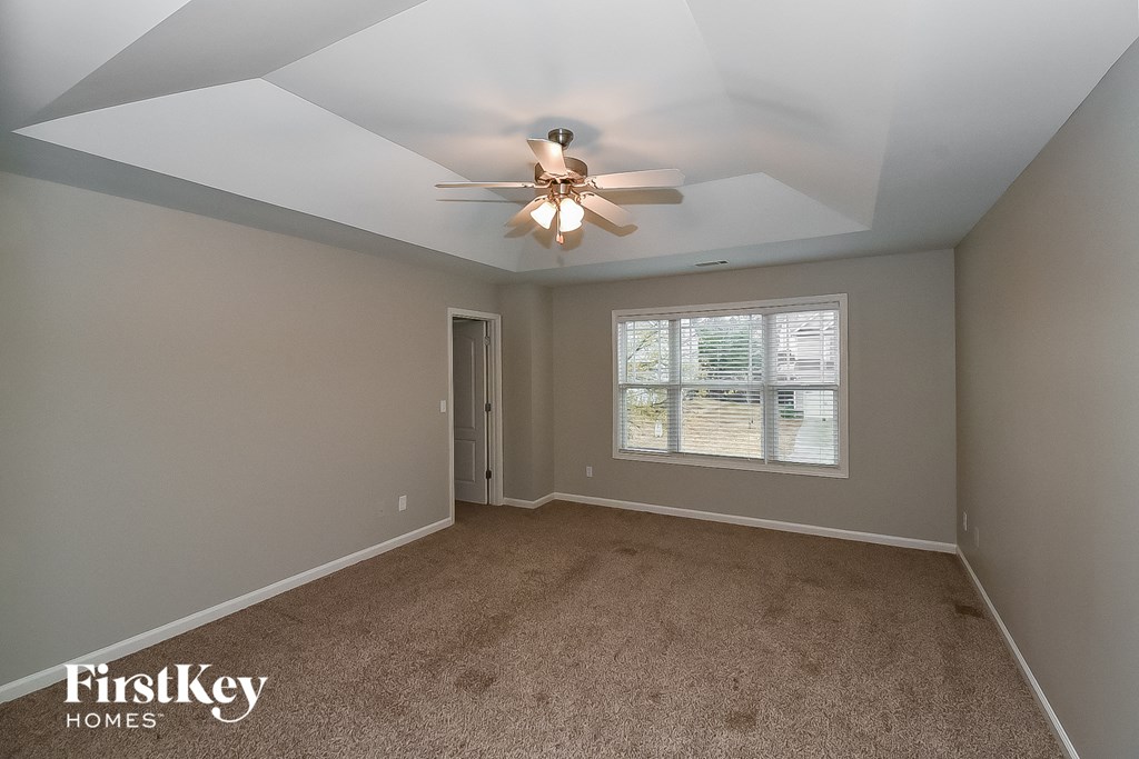 A spacious room with a ceiling fan and carpeted floor.
