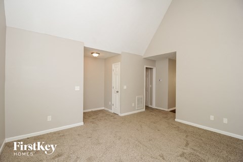 a spacious living room with carpet and a door to a closet