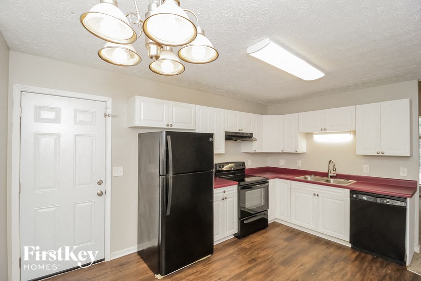 a kitchen with white cabinets and a black refrigerator