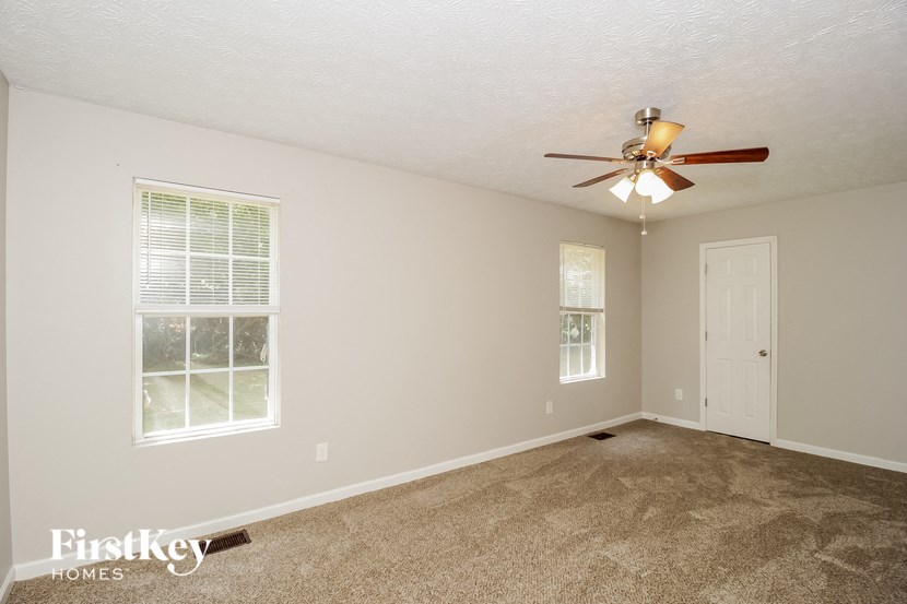 an empty living room with a ceiling fan and a window