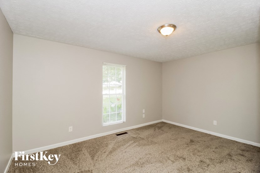 the living room of a home with carpet and a window