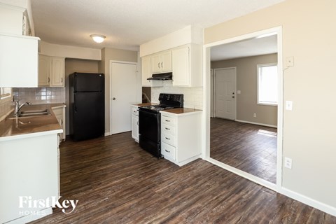 A kitchen with a black refrigerator and white cabinets.